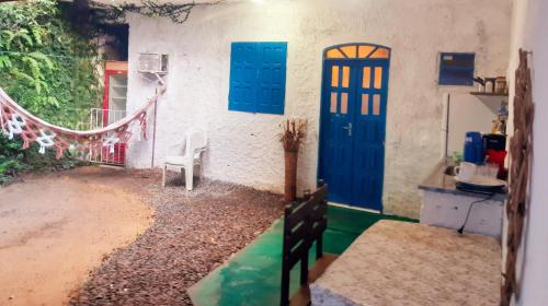 a house with blue doors and a chair in a yard at Casinha Guiné MorroSP in Morro de São Paulo