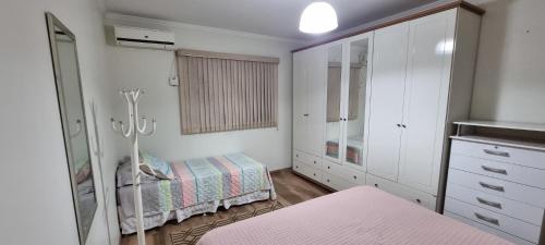 a white bedroom with a bed and a dresser at Casa no centro aproveite o melhor de Foz in Foz do Iguaçu