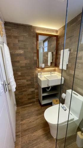 a bathroom with a sink and a toilet and a mirror at Nô Centro Suítes Florianópolis 1 in Florianópolis