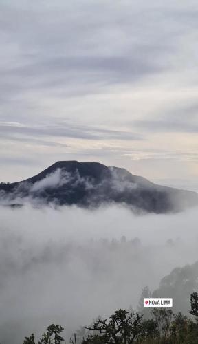 a mountain in the clouds with a sign in the foreground at Casa Vilas Boas Macacos in Nova Lima