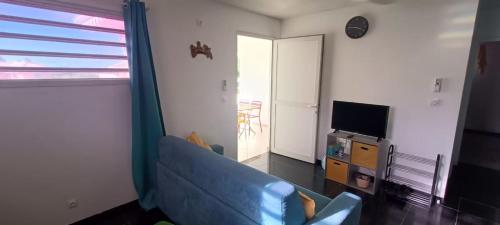 a living room with a blue couch and a television at Appartement F2 en résidence avec piscine et plage à 5min à pied in Les Trois-Îlets