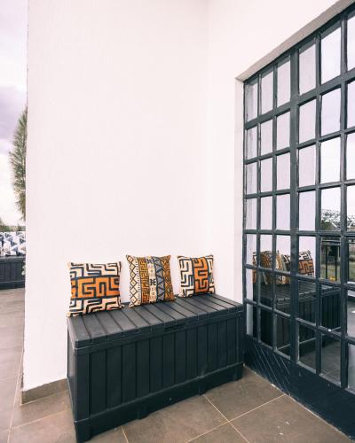 a black bench with pillows on a patio at Skyhut Boutique House Rooftop with LED-LIT DOME & Private Pool - Nairobi in Kitengela 