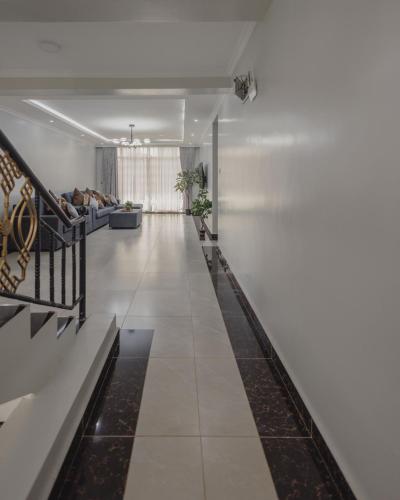 a hallway with white walls and white floors and benches at Skyhut Boutique House Rooftop with LED-LIT DOME & Private Pool - Nairobi in Kitengela 