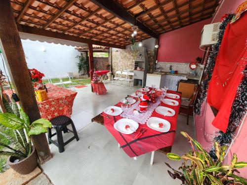 a dining room with a long table with red table cloth at Casa da Dinda à 650m da praia de Itaúna in Saquarema