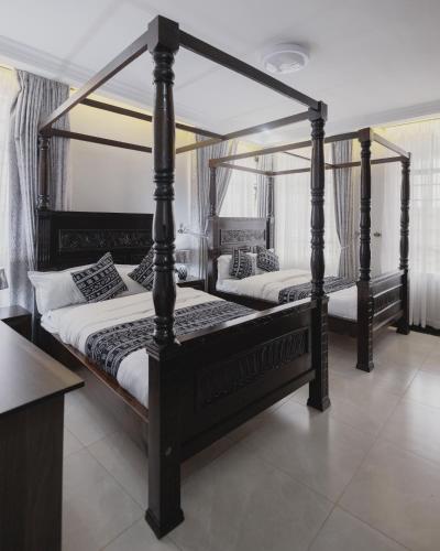 two four poster beds in a room at Skyhut Boutique House Rooftop with LED-LIT DOME & Private Pool - Nairobi in Kitengela 