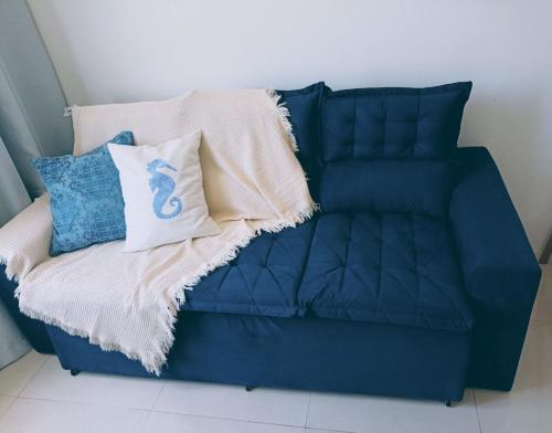 a blue couch with a blanket and pillows on it at Maresia in Passo De Torres