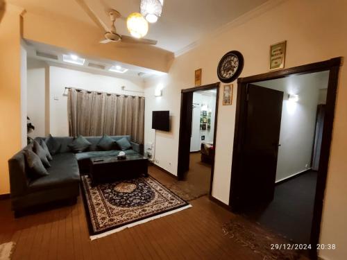 a living room with a couch and a clock on the wall at Luxury 2BR Family Apt/Wi-Fi / Netflix in Islamabad