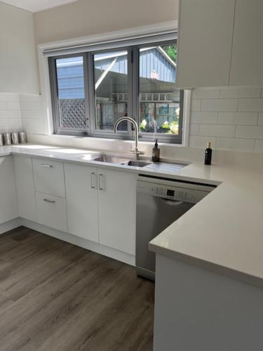 a white kitchen with a sink and a window at Emerald Haven in Upper Hutt