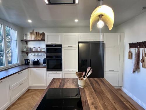 - une cuisine avec une table en bois et un réfrigérateur noir dans l'établissement Villa Mimpi - Castres, France, à Castres