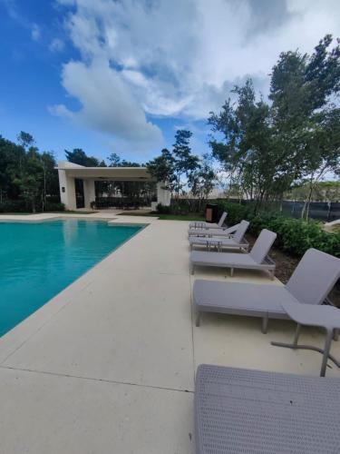 a row of white lounge chairs next to a swimming pool at Casa Kulkana 194 in Cancún