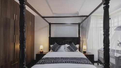 a bedroom with a black canopy bed with pillows at Skyhut Boutique House Rooftop with LED-LIT DOME & Private Pool - Nairobi in Kitengela 