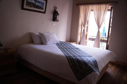a bedroom with a white bed with a window at Land of the Sun Hotel & Spa in Cotacachi