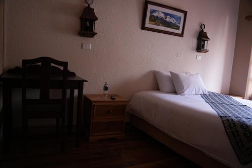 a bedroom with a bed and a chair and a table at Land of the Sun Hotel & Spa in Cotacachi