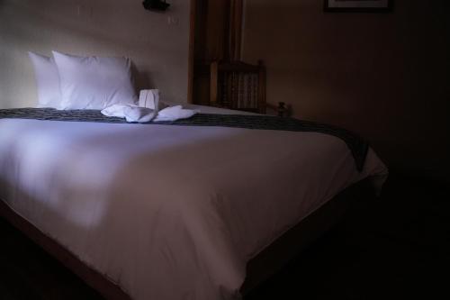 a large white bed with two towels on it at Land of the Sun Hotel & Spa in Cotacachi