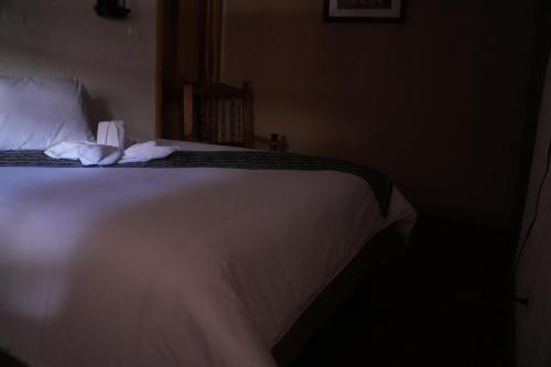a bedroom with a bed with white sheets and pillows at Land of the Sun Hotel & Spa in Cotacachi