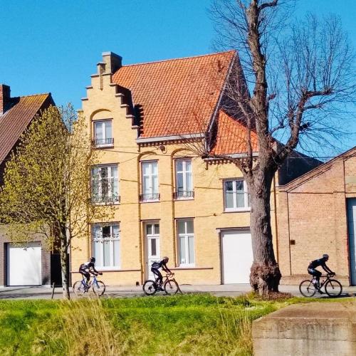 three people riding bikes in front of a building at Huyze Vinck in Veurne