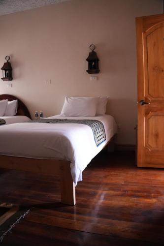 a bedroom with a large bed with white sheets at Land of the Sun Hotel & Spa in Cotacachi