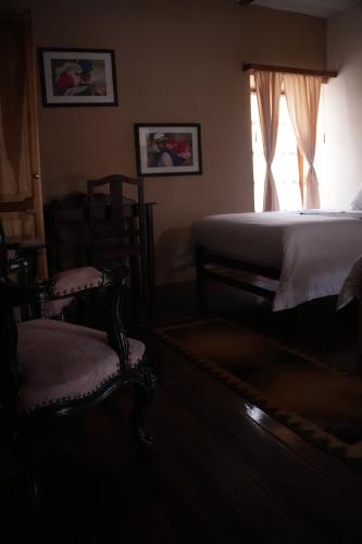 a bedroom with a bed and two chairs and a window at Land of the Sun Hotel & Spa in Cotacachi