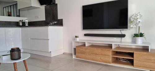 un salon avec une télévision sur un mur blanc dans l'établissement Village Naturiste Cap d'Agde Le Juliette Coursive, au Cap d'Agde