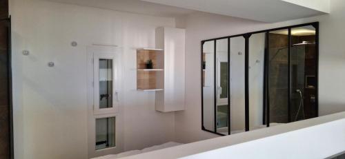 Cette chambre blanche dispose d'un miroir mural. dans l'établissement Village Naturiste Cap d'Agde Le Juliette Coursive, au Cap d'Agde