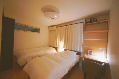 a bedroom with two beds and a desk and a window at 木漏の宿 in Osaka