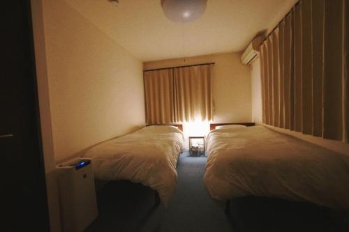 a hotel room with two beds and a window at 木漏の宿 in Osaka