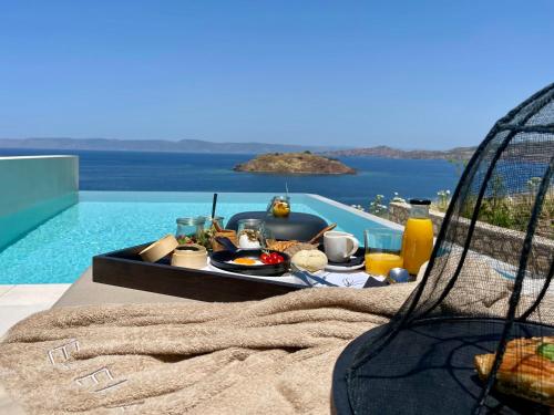 a tray of food on a table next to a pool at Eleia Seafront Rooms & Villas in Petra