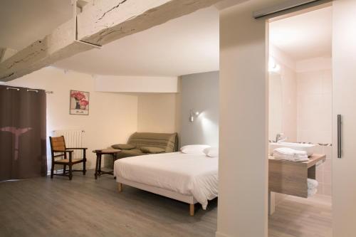 een slaapkamer met een bed, een bureau en een stoel bij Hotel Restaurant Le Sully in Saint-Saud-Lacoussière