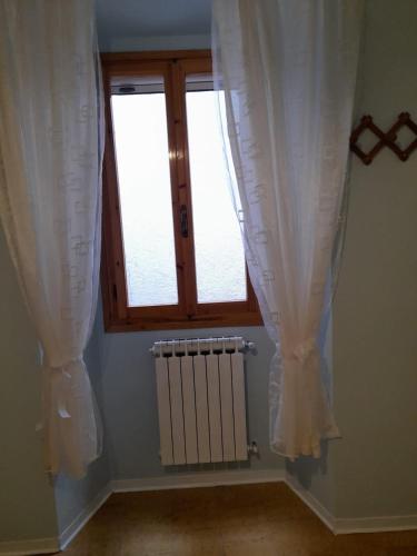 a room with two windows with curtains and a radiator at Casa Angiolino, angolo di pace vicino all'Orrido di Gea in Villa dʼAiano