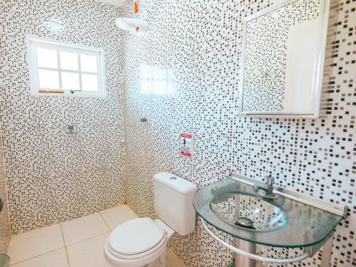 Un baño con inodoro y lavabo de cristal. en Pousada Sol Nascente, en Ubatuba