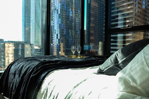 a bed in a room with a view of a city at Metropolitan Muse in Melbourne