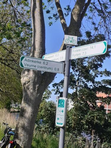a pole with street signs in front of a tree at Huyze Vinck in Veurne