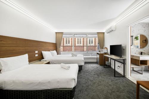 a hotel room with two beds and a television at Kingsway Motel Geelong in Geelong