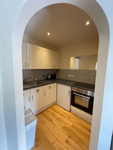 an arched kitchen with white cabinets and a wooden floor at Logan's Family Rest in Edinburgh