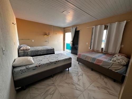 two beds in a room with two windows at Lessa imob in Salinópolis