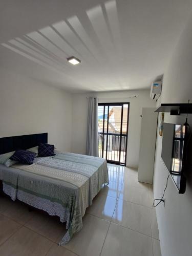 a white bedroom with a bed and a large window at Pousada Vista da Lagoa in Florianópolis