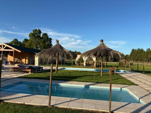 a pool with two straw umbrellas and a resort at Las Torres del Sol in Villa Lía