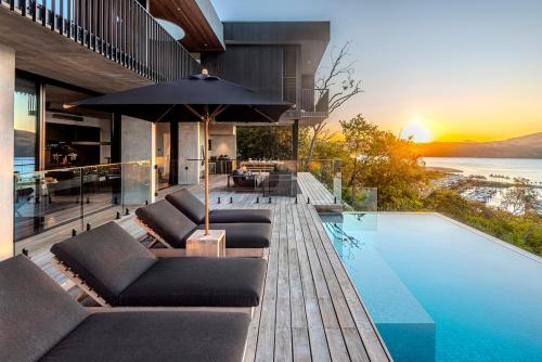 a house with a swimming pool with chairs and an umbrella at Haven House at Hamilton Island in Hamilton Island