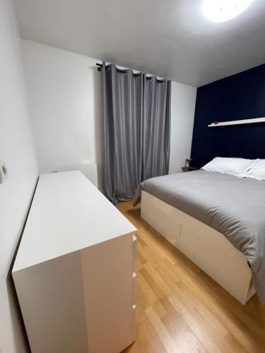 - une chambre avec un lit blanc et un mur bleu dans l'établissement Magnifique Appartement Moderne, à Villeneuve-le-Roi