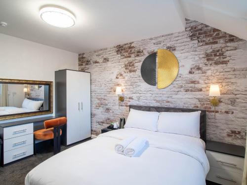 a bedroom with a white bed and a brick wall at Norfolk Heritage Park Rooms - Sheffield in Victoria