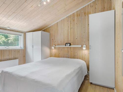 a bedroom with a white bed and wooden walls at Holiday home with spacious garden in Løkken
