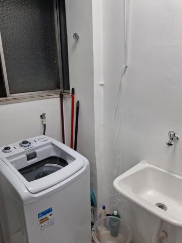 ヴィトーリアにあるApartamento na Praia do cantoの洗面台と洗濯機を備えた小さなバスルーム