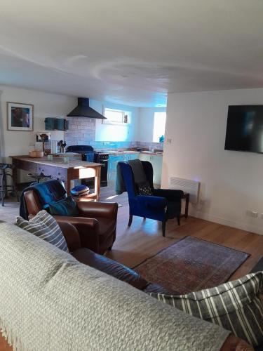 a living room with a couch and chairs and a kitchen at Wee Blue Hoose in Dalmally