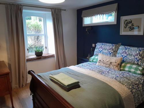 a bedroom with a bed with blue walls and a window at Wee Blue Hoose in Dalmally