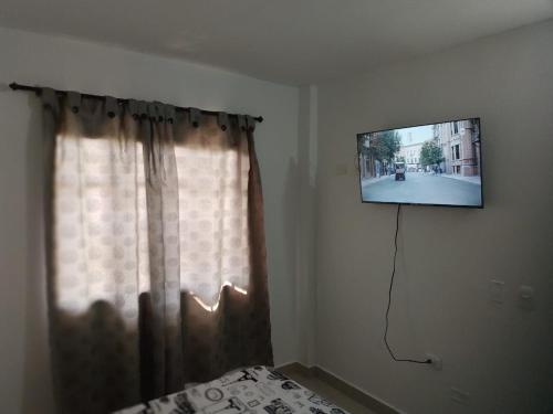 a tv hanging on a wall next to a window at Los primos 2 in Santa Marta