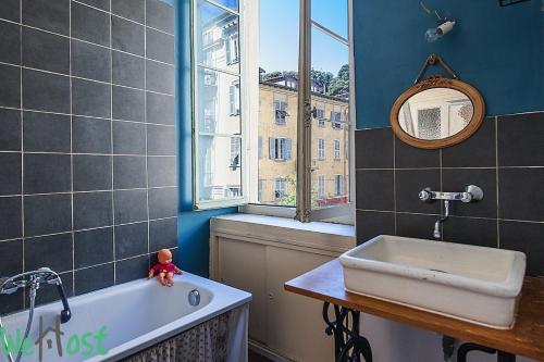 une salle de bain avec une baignoire, un lavabo et une fenêtre dans l'établissement L'Ecrin Vintage So NICE, à Nice