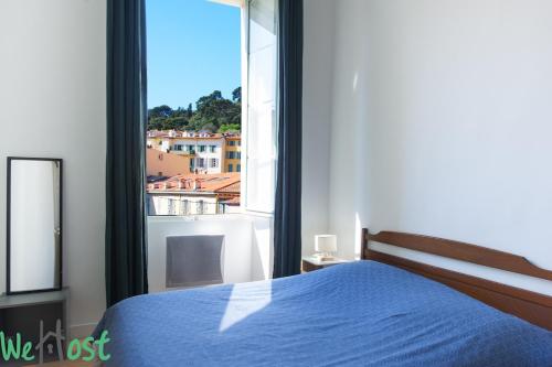 une chambre avec un lit bleu et une grande fenêtre dans l'établissement L'Ecrin Vintage So NICE, à Nice