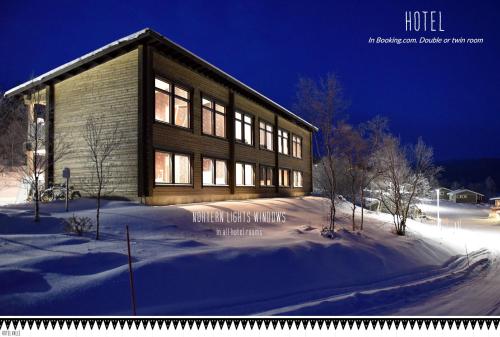 a large wooden building in the snow with snow at Hotel Valle Lapland in Utsjoki