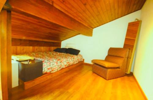 une chambre avec un lit et une chaise dans l'établissement Apto Pirineos Osseja, à Palau-de-Cerdagne