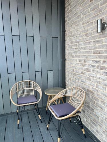 two wicker chairs and a table on a deck at Cozy, Stylish SHARED Flat - Bexleyheath London in Bexleyheath